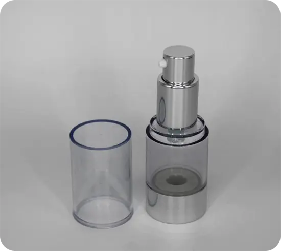 A clear cylindrical spray bottle with a silver base and nozzle is shown against a plain backdrop. The bottle's transparent cap is removed and placed beside it.